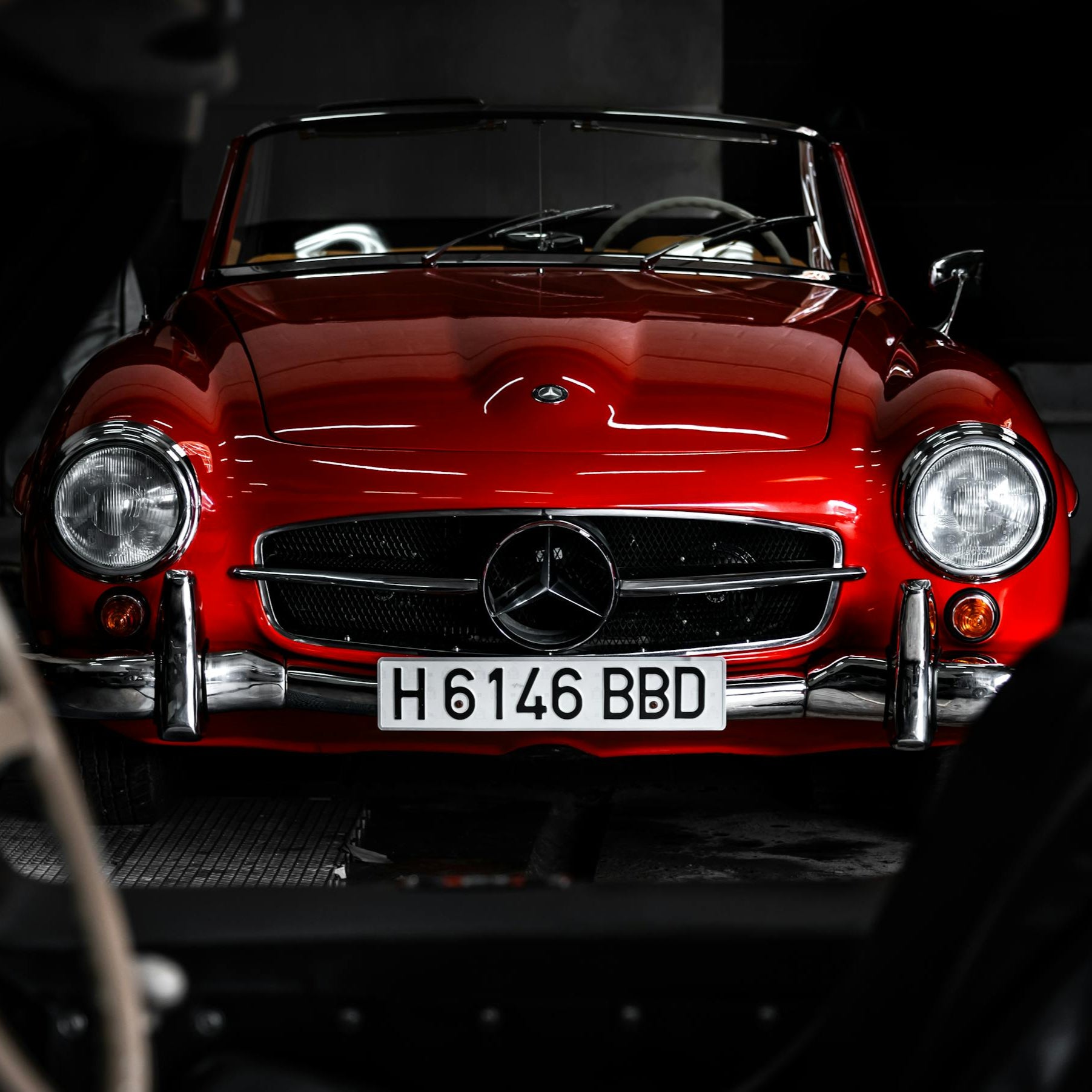 Red Mercedes-Benz car with a visible license plate in a dark setting