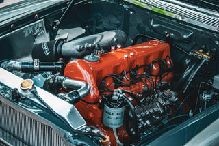 Close-up of a restored classic Mercedes-Benz inline engine bay with original orange engine paint