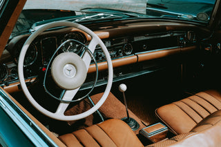 Interior view of a classic Mercedes-Benz W113 Pagoda showing the steering wheel, dashboard and tan leather seats